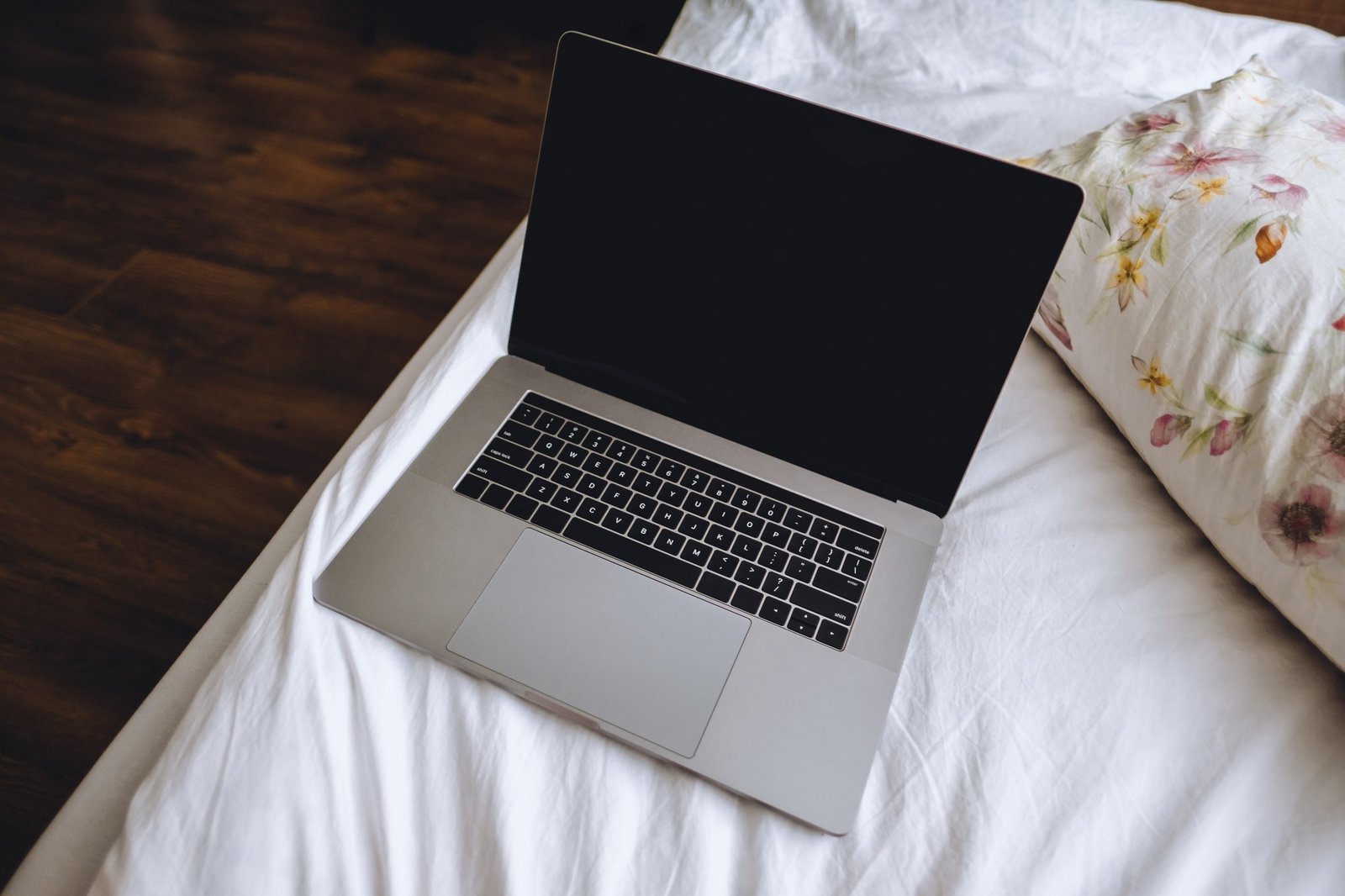 Laptop liegt auf einem Bett mit weicher Decke