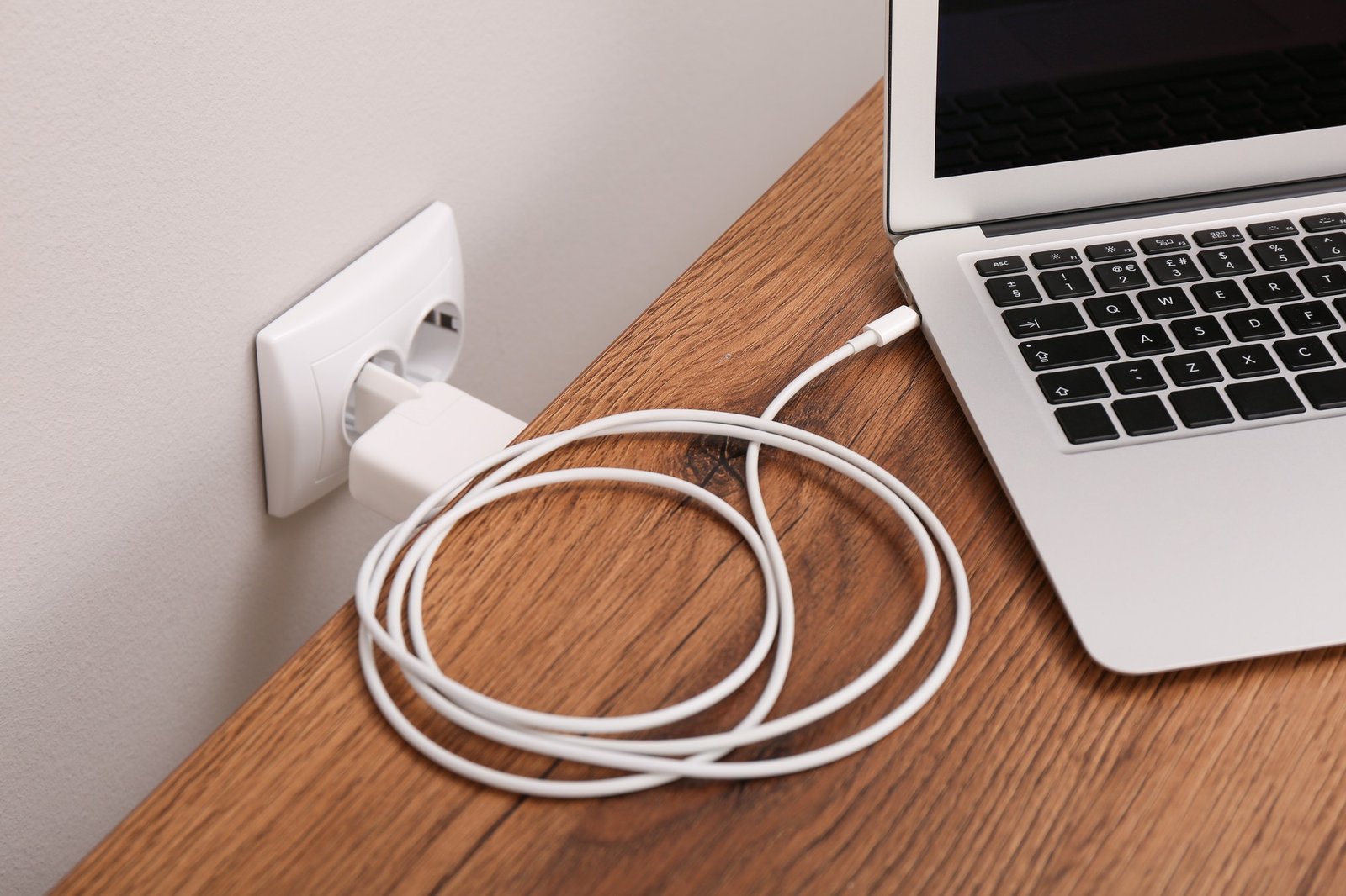 Laptop mit angeschlossenem Ladekabel auf dem Tisch